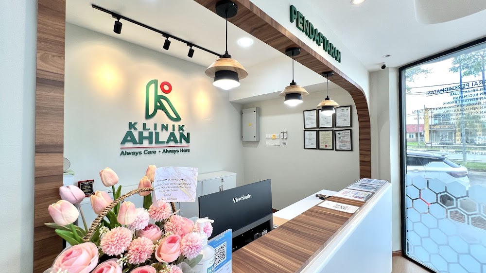 Kaunter pendaftaran Klinik Ahlan dengan logo dan bunga segar
