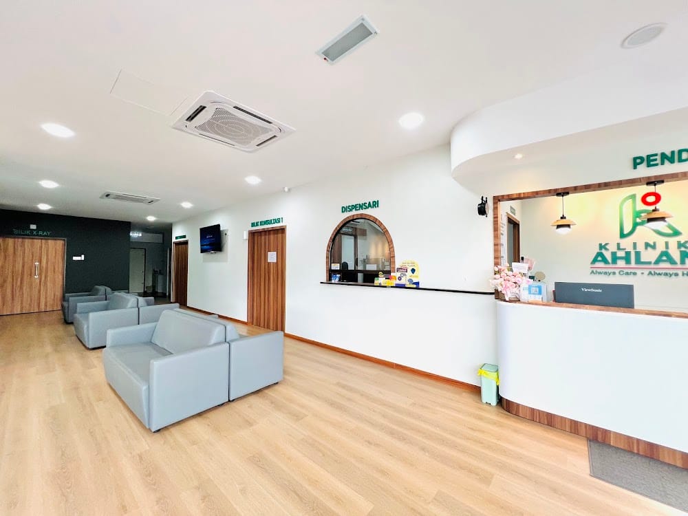 Ruang menunggu Klinik Ahlan dengan sofa kelabu dan kaunter dispensari